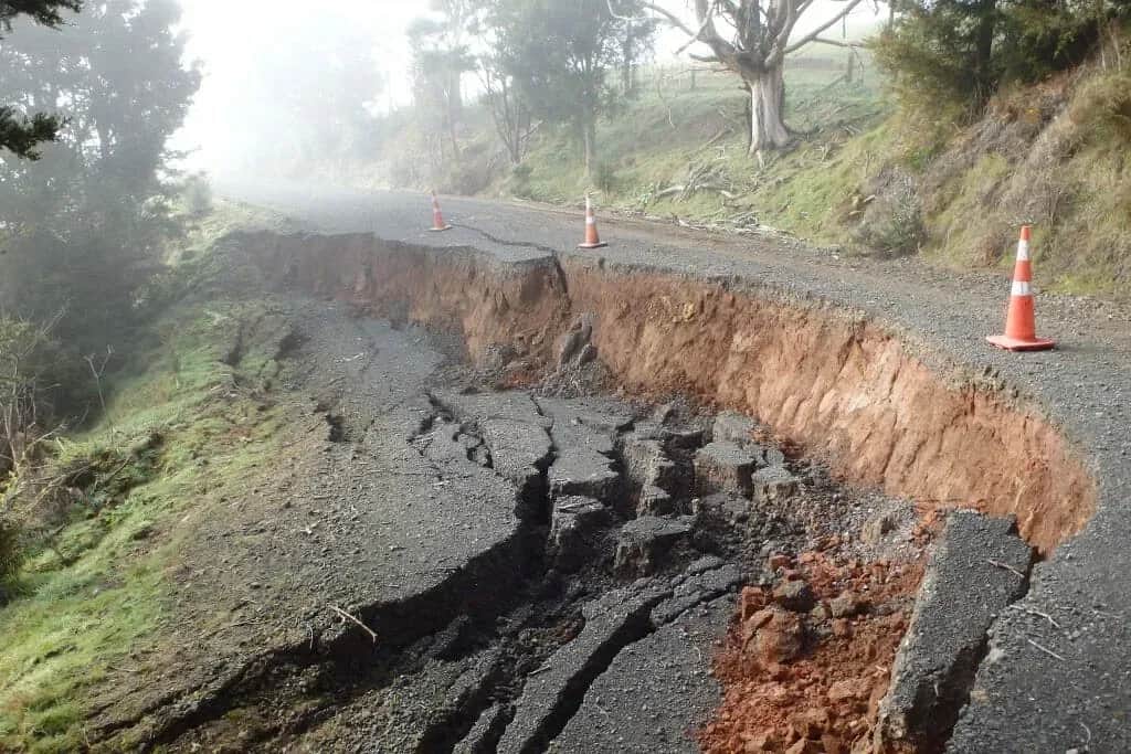 Collapsed road edge in red-brown Northland clay on Gammons Road, cordoned with traffic cones