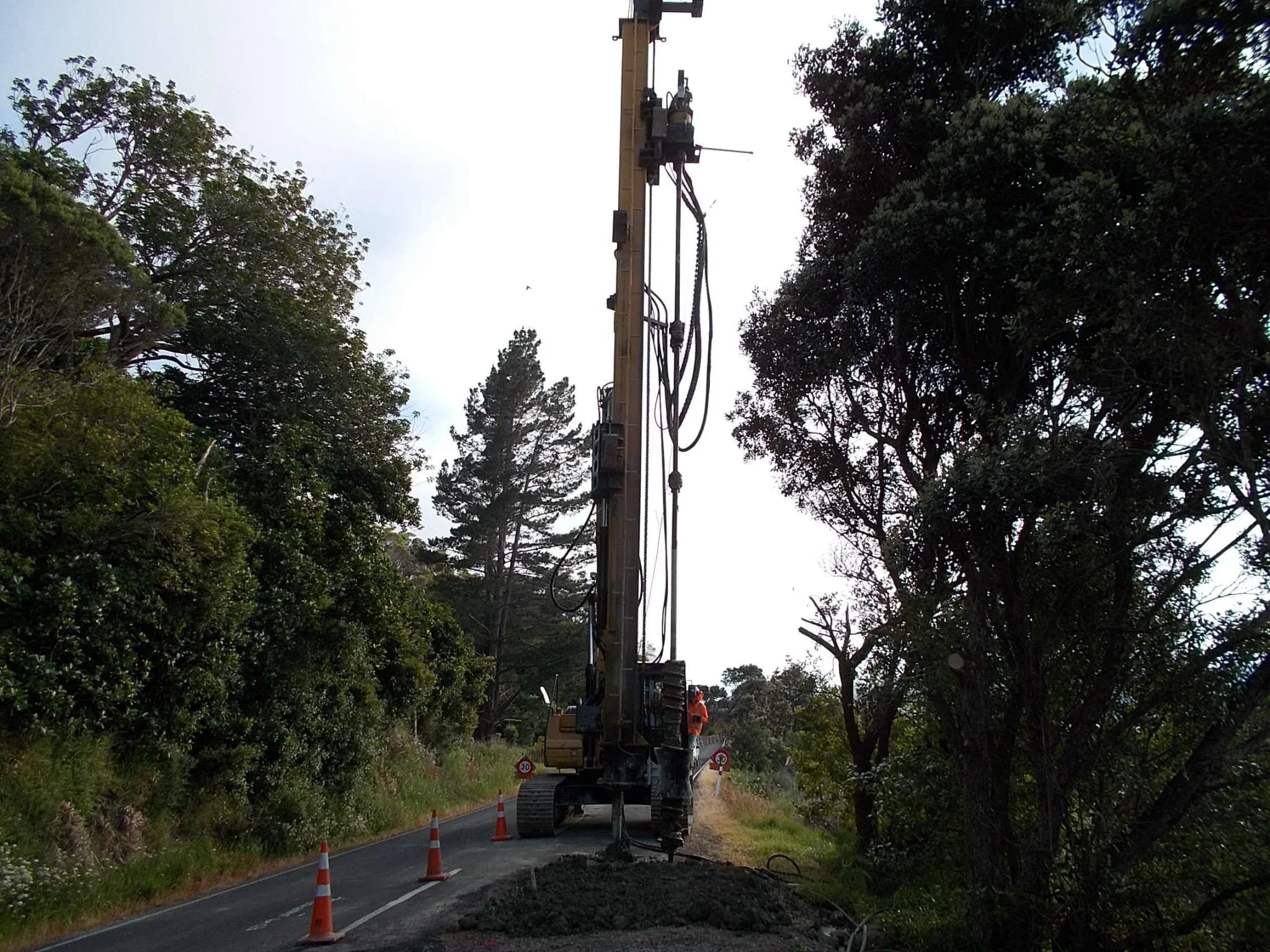 Close-up of a drilling rig auger beside an exposed soil face