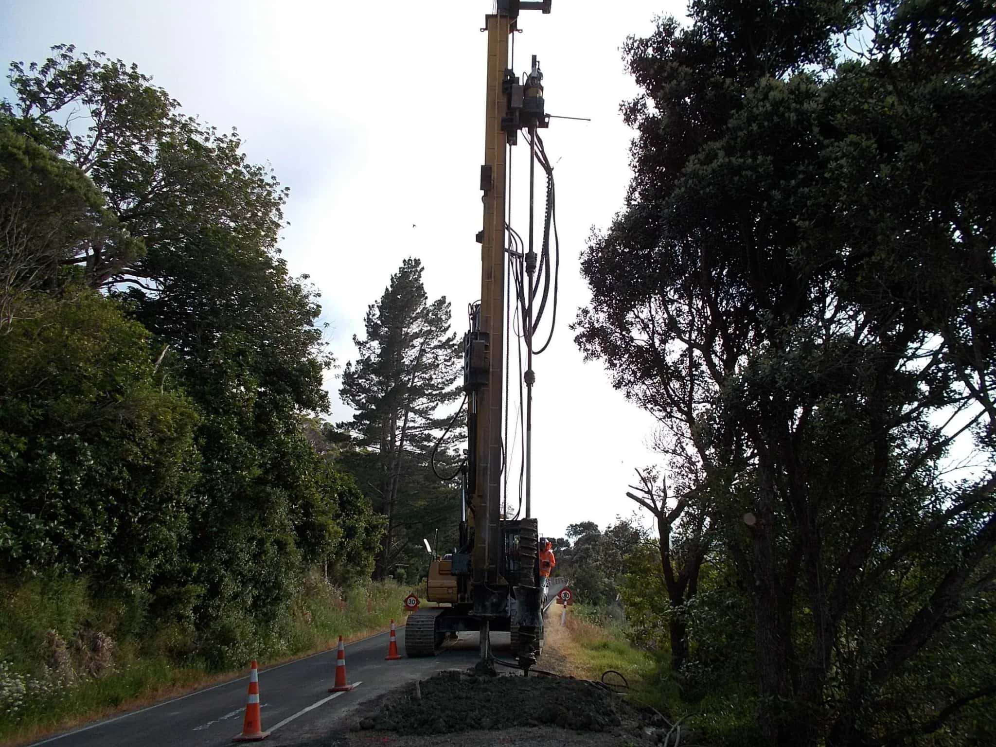 Close-up of a drilling rig auger beside an exposed soil face
