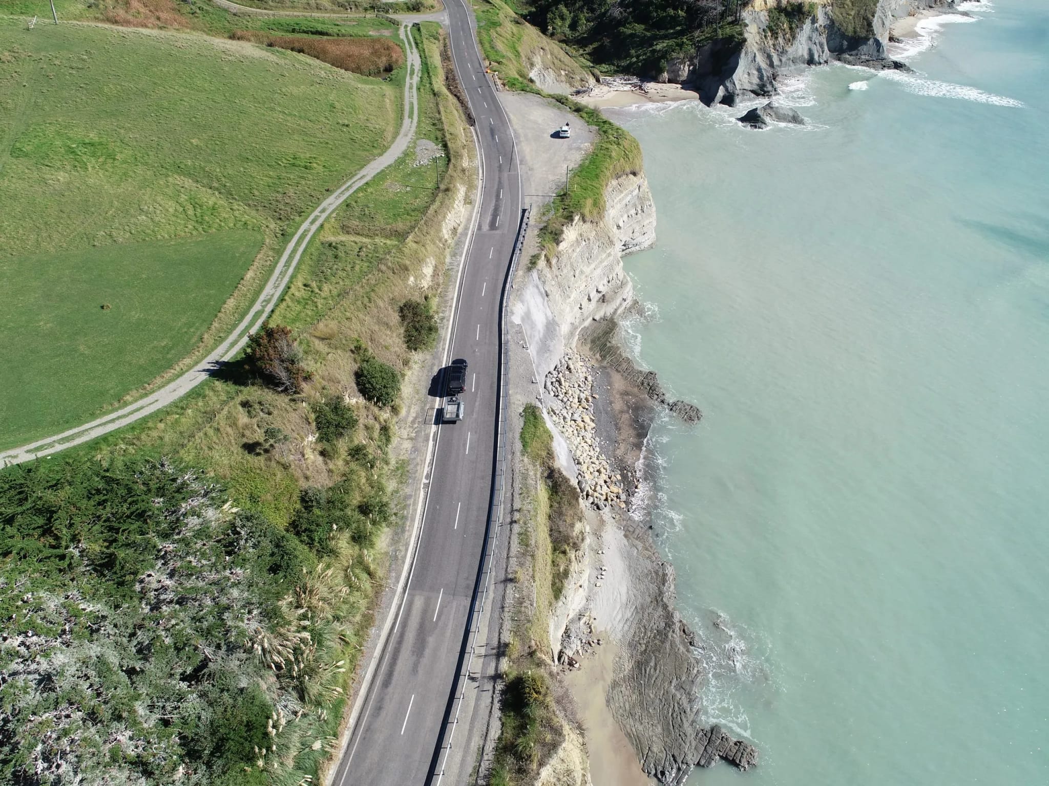 Aerial view of a coastal highway on a cliff edge above the sea