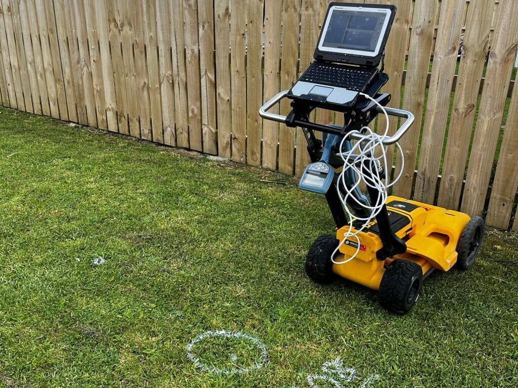 A gpr machine on grass next to a fence