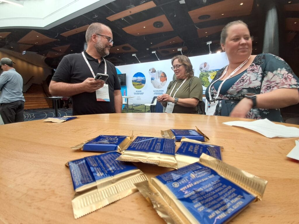 a group of people standing around a table with blue packets