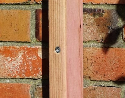 close up of python c screws joing timber to brick